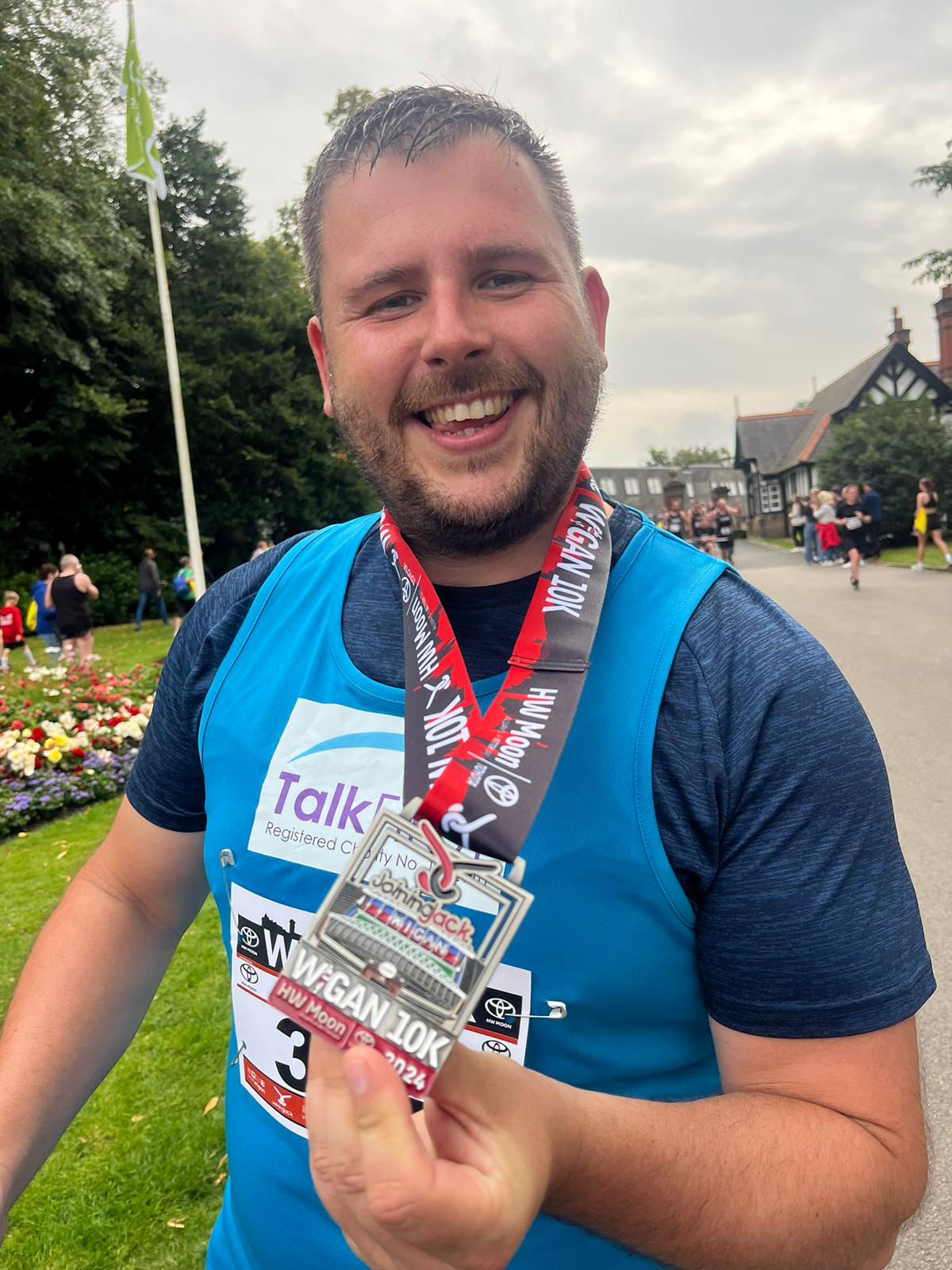 Healthwatch runner wearing the Wigan 10k Medal