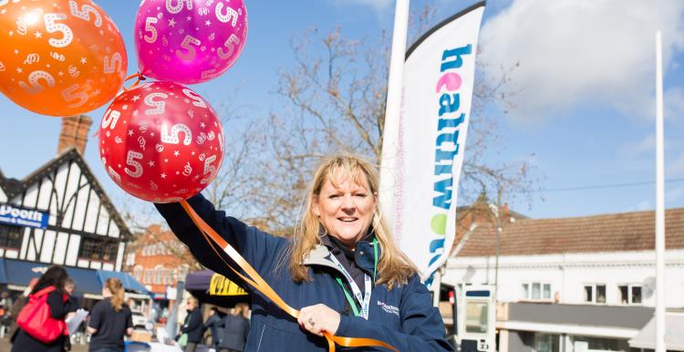 Healthwatch staff member holding balloons at a community event