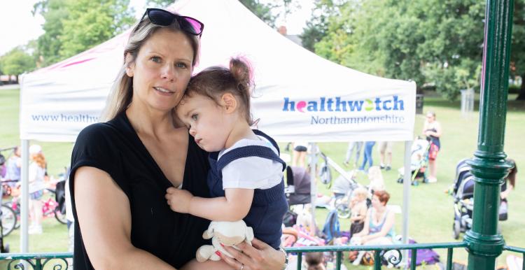 Mother holding her daughter on her hip at a Healthwatch event 