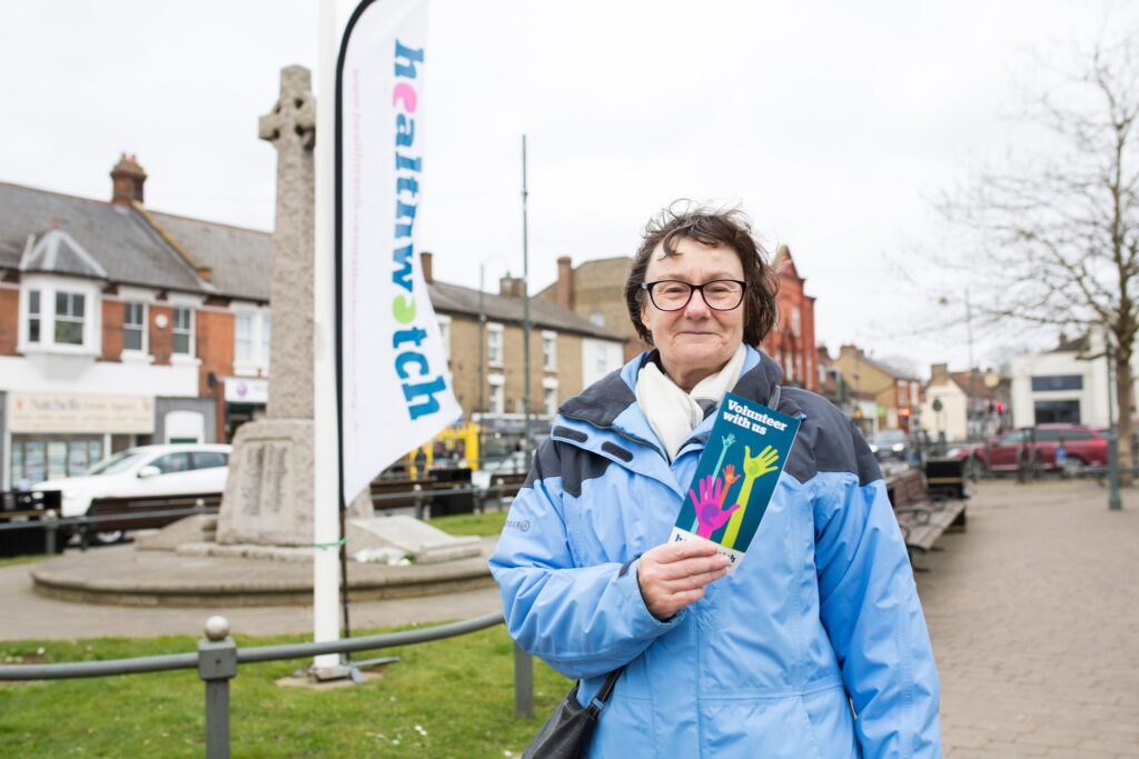 Old woman holding a flyer with Healthwatch colours.